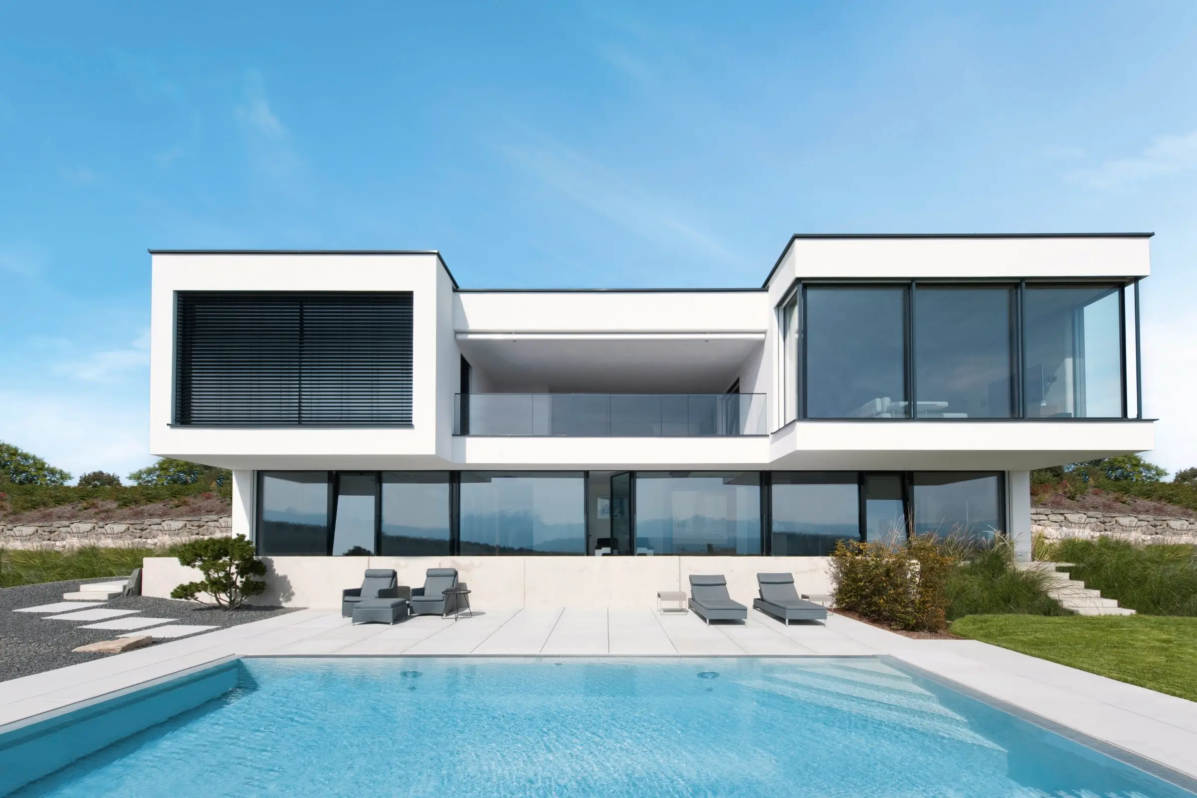 Modern white house with large triple-glazed windows beside a swimming pool